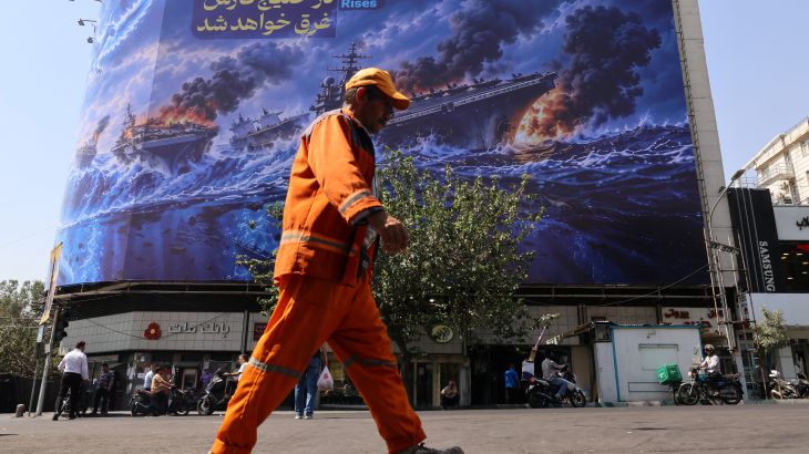 Iranian commuters pass a huge anti-US billboard reading in Persian, The devil army will be drowned in the Persian Gulf, erected on Enghelab Square in Tehran, on September 14, 2026. Iran's nuclear chief was blocked from attending an annual conference on September 14, at the headquarters of the UN's nuclear agency in Vienna due to opposition from the United States, Iranian state television said. He was due to attend the annual general conference of the International Atomic Energy Agenc