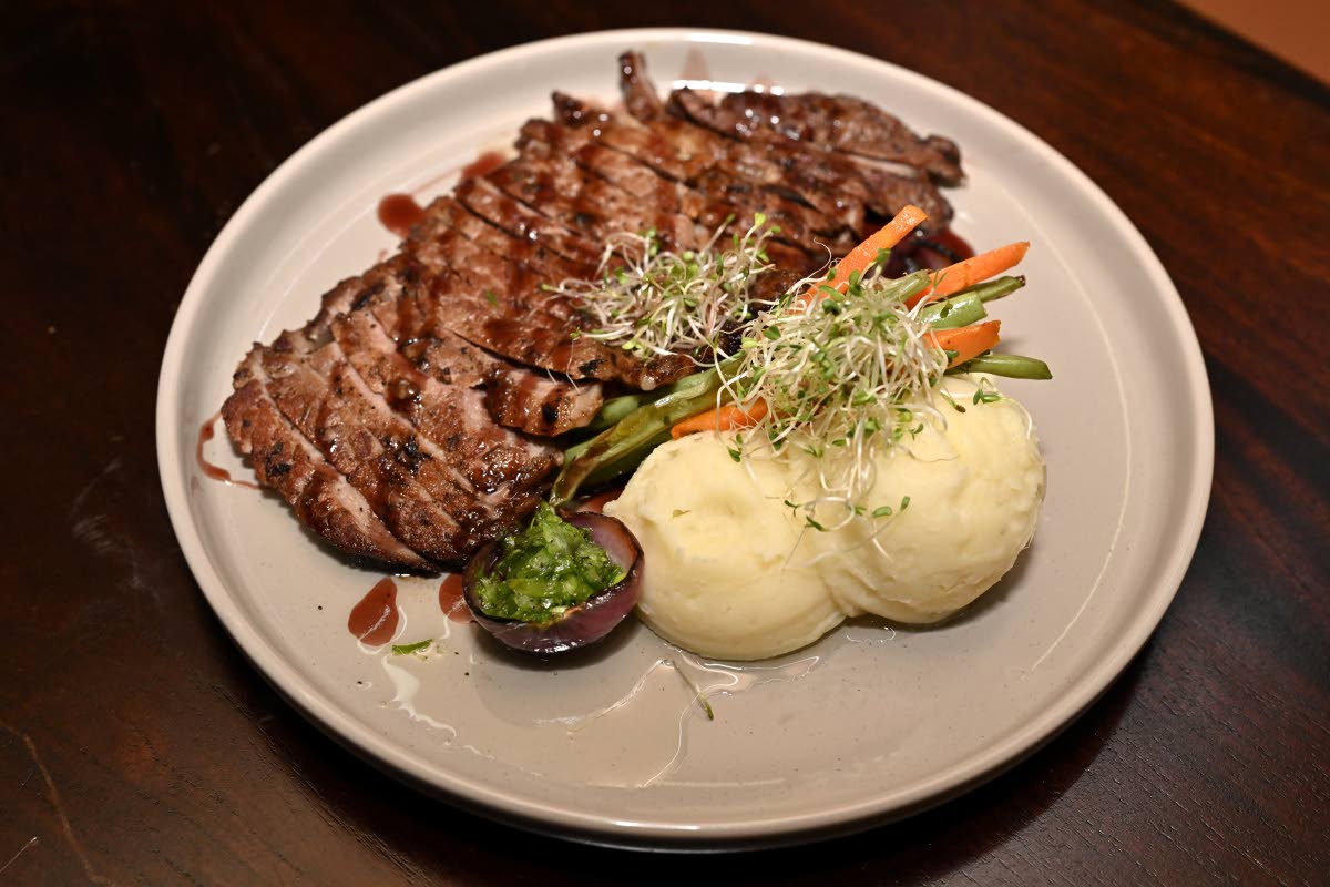 The chairman’s ribeye is a pan-seared ribeye steak served with creamy garlic mashed potatoes and seasonal vegetables, finished with a sweet red wine reduction in a chimichurri sauce.