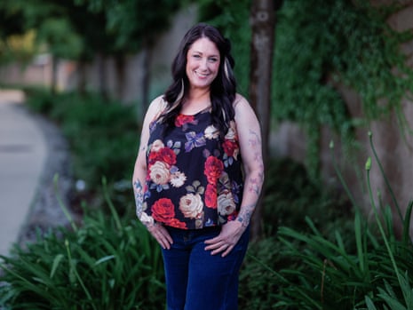Shauna Castaner smiling at the camera, standing on a grass verge next to a path with her thumbs in her pockets, wearing a sleeveless floral top and blue jeans