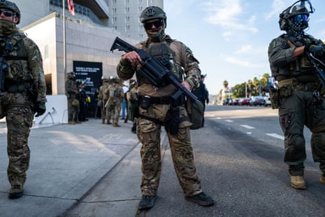 masked men in tactical gear hold guns outside